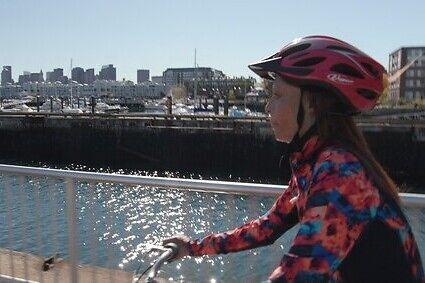 A young girl biking by a river
