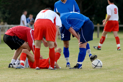 Soccer players huddled around injured teammate